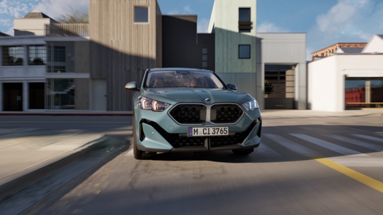 Vista frontal de SUV premium BMW X2 siendo conducido por calles residenciales.